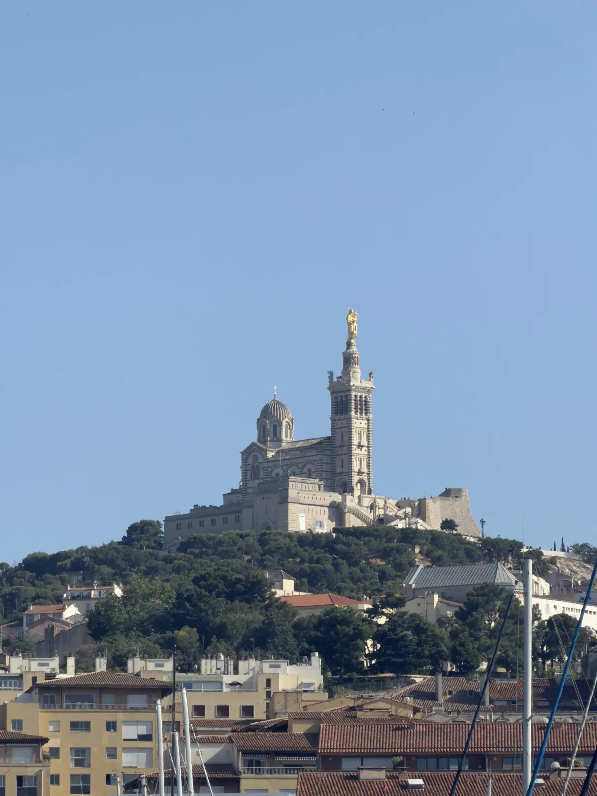 Vieux-Port de Marseille avec les mâts des bateaux et Notre-Dame de la Garde en arrière-plan.