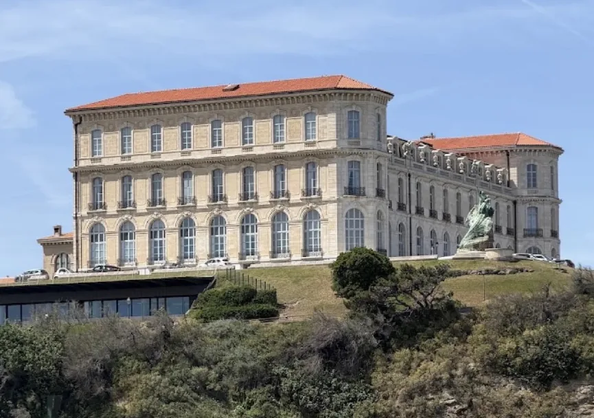 Vue du palais du Pharo à Marseille avec verdure au premier plan.